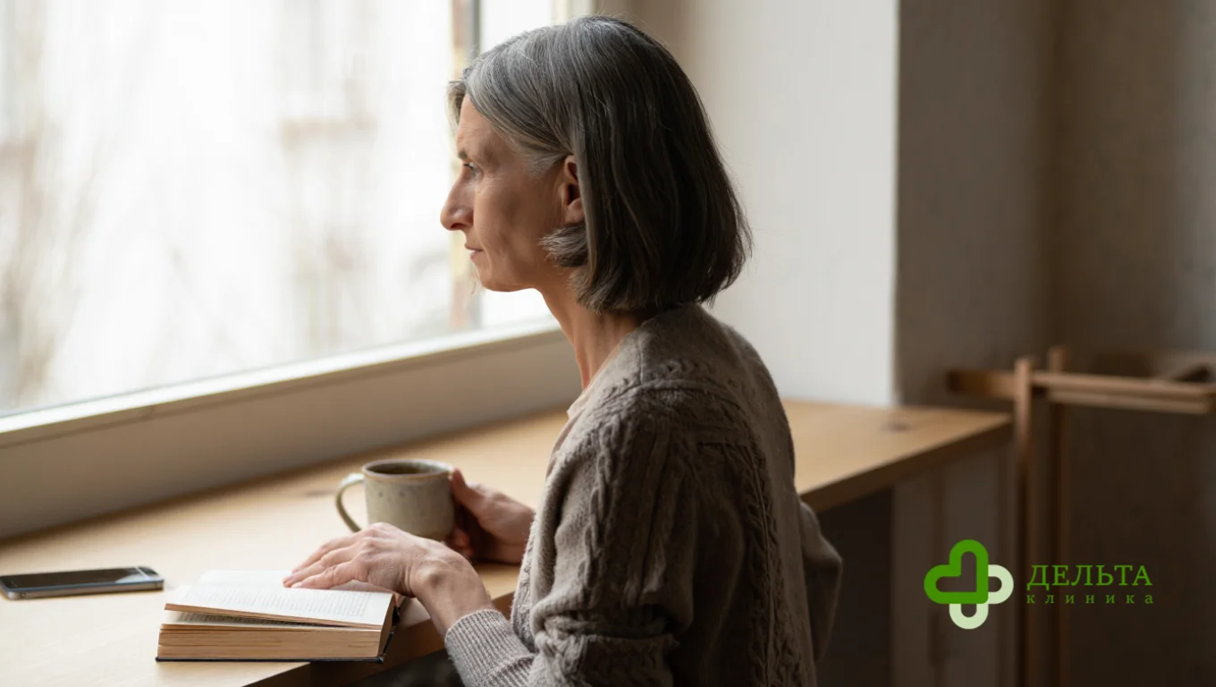 Женщина стоит у окна